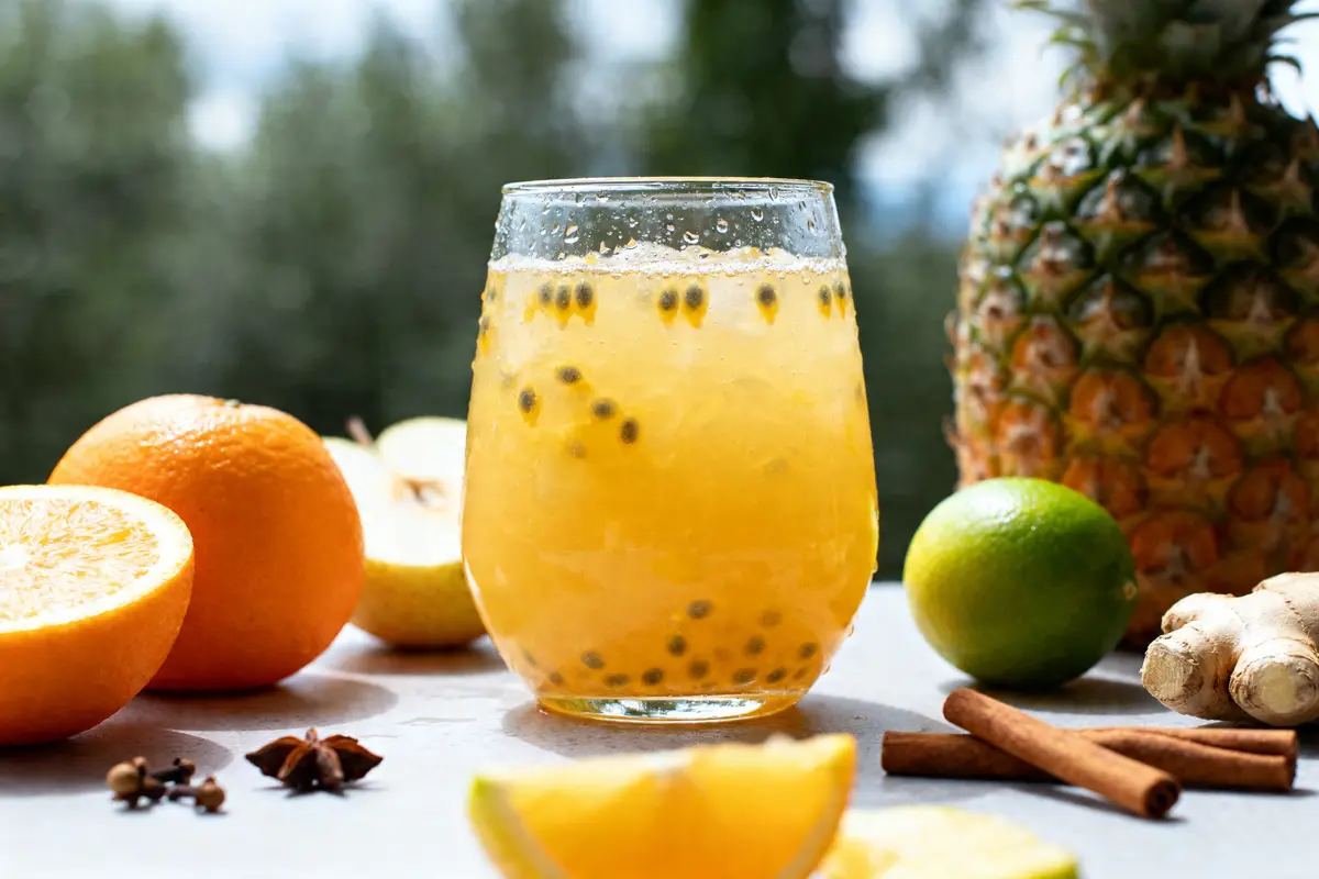 Verre de punch arrangé aux fruits exotiques avec orange, ananas et épices sur table